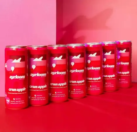 A row of six red Ayrloom cannabis-infused beverage cans lined up against a vibrant pink and red background.