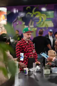 Customer at Nuna Harvest checkout counter wearing red plaid shirt