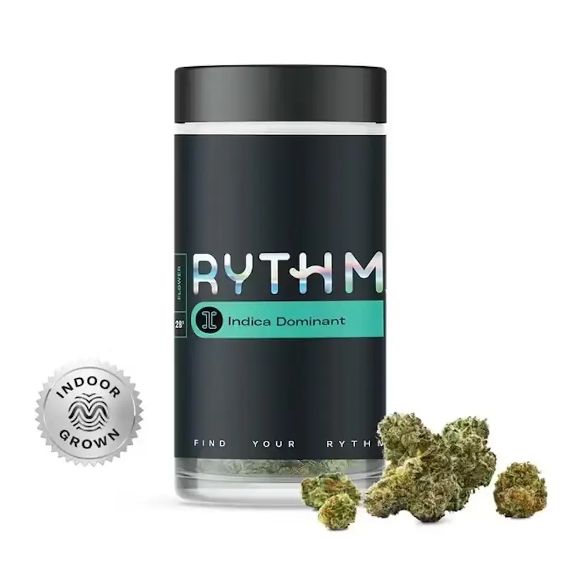 A tall, clear glass jar with a black label wrapped around it that features the word "RYTHM" in all-caps, light-colored letters on a plain white background.