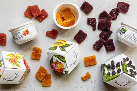 An assortment of Wyld fruit-flavored gummies scattered around white branded boxes and small serving containers.